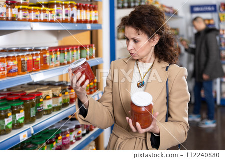 Adult woman chooses lecho in store 112240880