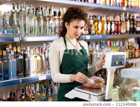 Woman works as salesperson in alcohol department of Russian store. 112240886