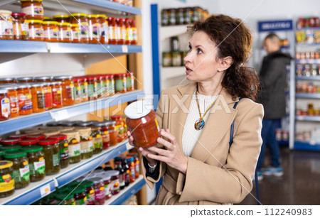 Adult woman chooses lecho in store Adult woman chooses lecho in store 112240983