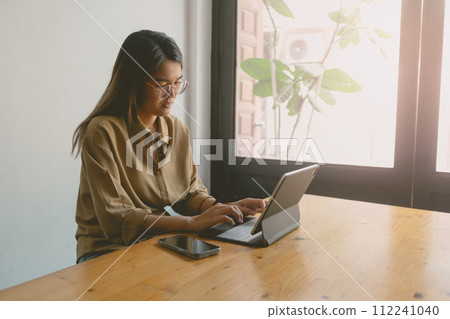 Digital nomad woman working online on the table of hostel while going abroad. Digital nomad woman working online on the table of hostel while going abroad. 112241040
