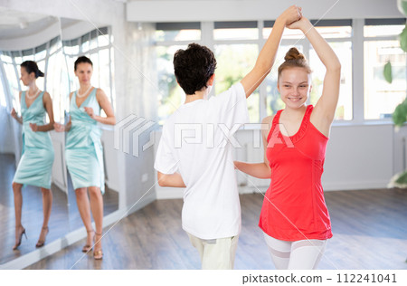 Teenage girl and boy practicing waltz in dance hall with female mentor Teenage girl and boy practicing waltz in dance hall with female mentor 112241041