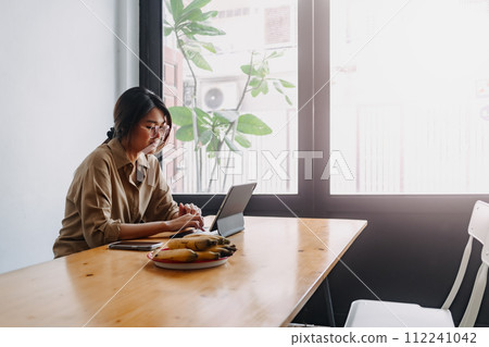 Digital nomad woman working online on the table of hostel while going abroad. Digital nomad woman working online on the table of hostel while going abroad. 112241042