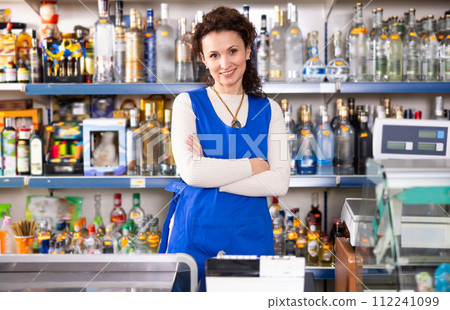Woman works as salesperson in alcohol department of Russian store. 112241099