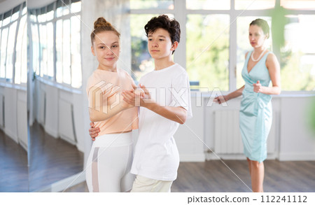 Teenage girl and boy practicing waltz in dance hall with female mentor 112241112