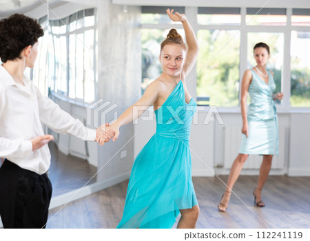 Teenage boy and girl performing waltz in pair during dance lesson 112241119
