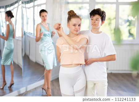 Adolescent dance duo, boy and girl, refining slow foxtrot with female coach Adolescent dance duo, boy and girl, refining slow foxtrot with female coach 112241133
