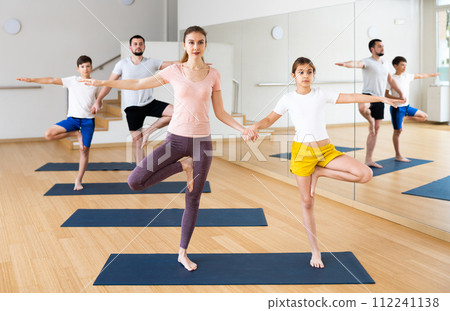 Family practicing yoga in pairs at gym 112241138