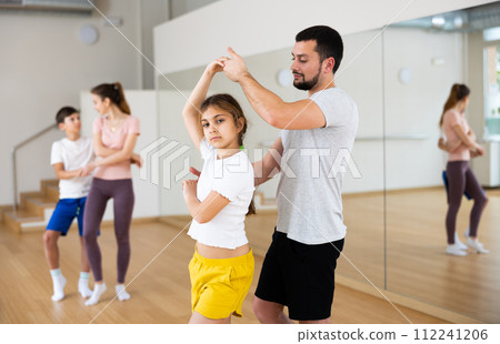 Young girl dancing waltz with her dad in gym 112241206