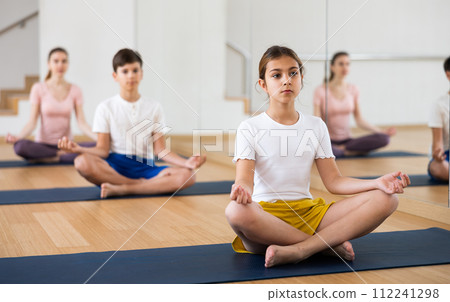 Teen girl meditating in Padmasana position during family yoga training 112241298