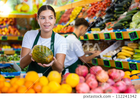 Young female seller puts melons on the counter Young female seller puts melons on the counter 112241342