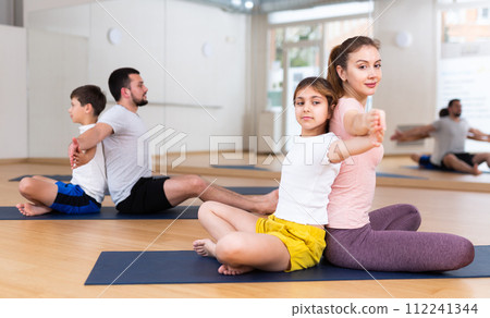 Children and parents sitting back to back on yoga mats 112241344