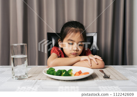 Little cute kid girl refusing to eat healthy vegetables. Children do not like to eat vegetables. Little cute kid girl refusing to eat healthy vegetables. Children do not like to eat vegetables. 112242609