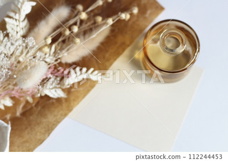 Dried white flowers and a small brown vase placed on brown waxed paper 112244453