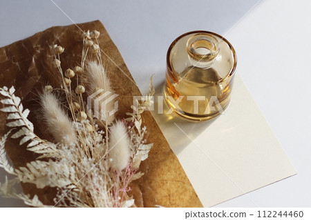 Dried white flowers and a small brown vase placed on brown waxed paper Dried white flowers and a small brown vase placed on brown waxed paper 112244460