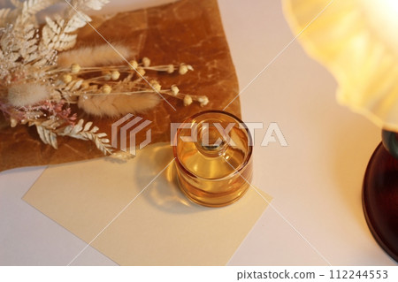 White dried flowers placed on brown waxed paper and a small brown vase with light bulb-colored lights White dried flowers placed on brown waxed paper and a small brown vase with light bulb-colored lights 112244553