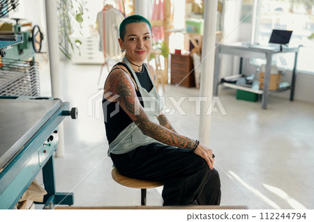 Creative female designer sitting on background of print machine in workshop Creative female designer sitting on background of print machine in workshop 112244794