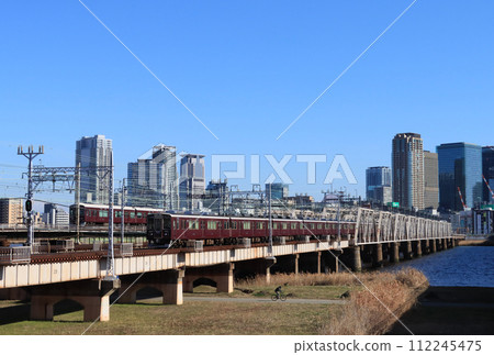 Hankyu train crossing the Yodo River and skyscrapers in Umeda, Osaka 112245475