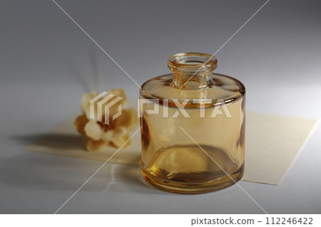 A single beige dried flower and a small brown vase 112246422