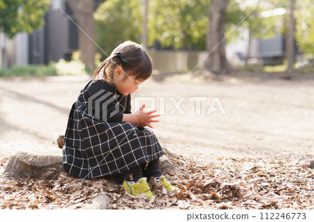 坐在公園樹樁上的小女孩 坐在公園樹樁上的小女孩 112246773