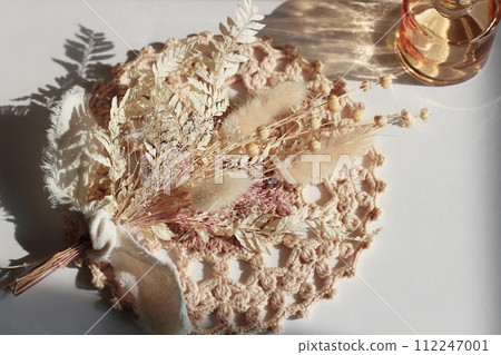 乾燥白花和放在棕色蠟紙上的小棕色花瓶 112247001