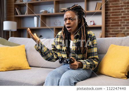 Surprised African American Woman Playing Video Games on Couch 112247440