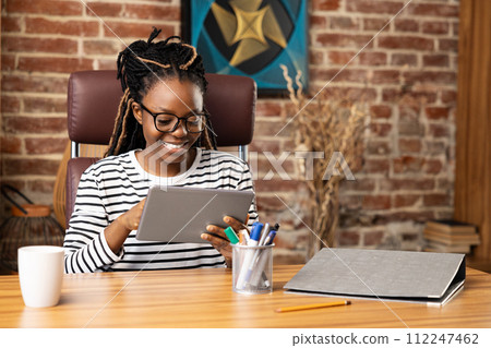 Happy Afro American Woman Using Tablet for Video Call at Home Happy Afro American Woman Using Tablet for Video Call at Home 112247462