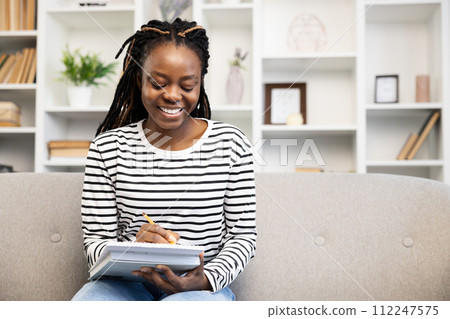 Smiling African American Woman Enjoying Leisure Time at Home Smiling African American Woman Enjoying Leisure Time at Home 112247575
