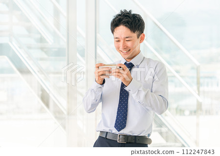Young Asian businessman playing games on smartphone during break in office 112247843