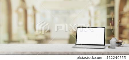 A white marble table features a white-screen laptop mockup in a contemporary, cosy coffee shop. A white marble table features a white-screen laptop mockup in a contemporary, cosy coffee shop. 112249335