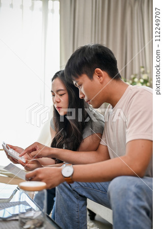 A lovely young Asian couple is planning their savings and managing their household bills together. 112249707