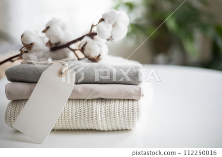 A neat stack of clean knitwear in neutral colors. Concept for sale, recycling and storage of clothing. Blank white label. 112250016