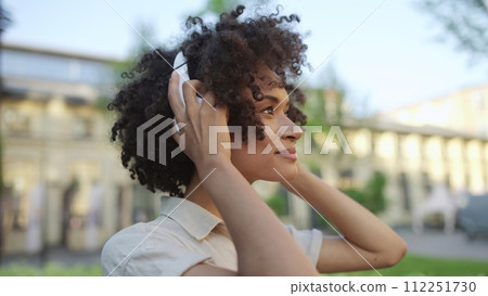 Young confident woman putting on headphones and going for a walk, freedom 112251730