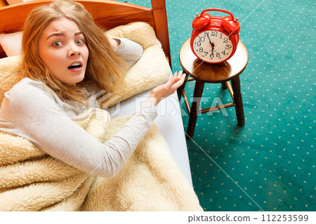 Woman waking up turning off alarm clock in morning Woman waking up turning off alarm clock in morning 112253599