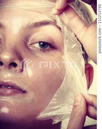 Woman removing facial peel off mask. 112253748
