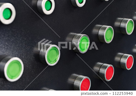 Red and green round lamps and buttons on black control panel 112253940