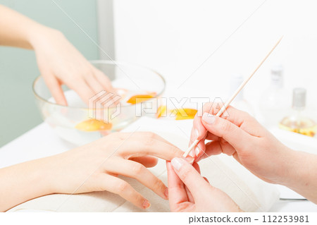 Preparing nails before manicure, pushing back cuticles 112253981