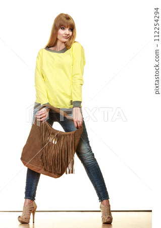 woman holds brown fringe handbag 112254294