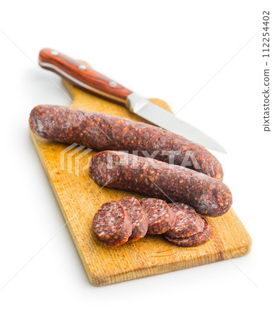 Sliced salami sausage on cutting board isolated on white background. 112254402