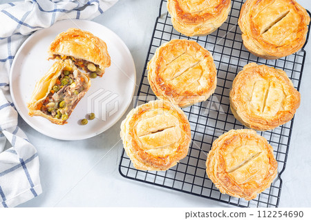 Sliced beef pot pie on plate and pies on cooling rack, horizontal, top view Sliced beef pot pie on plate and pies on cooling rack, horizontal, top view 112254690