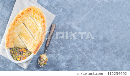 Beef pot pie or deep dish pie in baking dish, crust broken open, horizontal, top view, copy space Beef pot pie or deep dish pie in baking dish, crust broken open, horizontal, top view, copy space 112254692