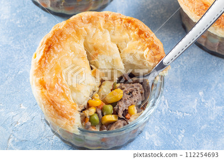 Individual beef pot pie or deep dish pie in ramekin, crust broken open to show inside, horizontal Individual beef pot pie or deep dish pie in ramekin, crust broken open to show inside, horizontal 112254693