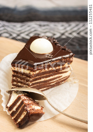 Chocolate layer cake with spoon. Biscuit cake with melted ganache on top. Slice of creamy tart. Vanilla and cacao layer dessert. Sweet food concept. Birthday cake close up. Chocolate layer cake with spoon. Biscuit cake with melted ganache on top. Slice of creamy tart. Vanilla and cacao layer dessert. Sweet food concept. Birthday cake close up. 112255481