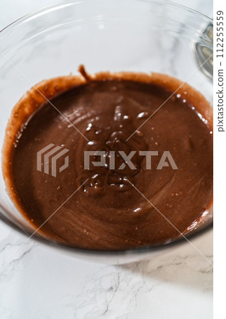 Cupcake foil liners are being meticulously filled with both chocolate and vanilla batter, setting the stage for the baking of deliciously diverse birthday cupcakes. Cupcake foil liners are being meticulously filled with both chocolate and vanilla batter, setting the stage for the baking of deliciously diverse birthday cupcakes. 112255559