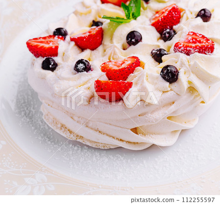 Pavlova cakes with cream and fresh berries on plate Pavlova cakes with cream and fresh berries on plate 112255597