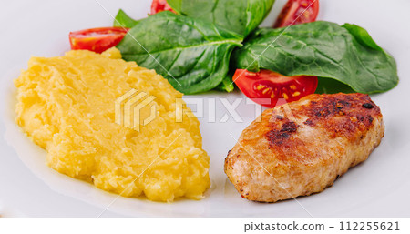 polenta with cutlet and cherry tomatoes with basil 112255621