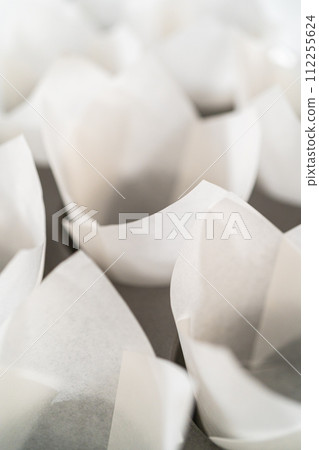 Lining baking cupcake pan with paper tulip liners to bake no-yeast cinnamon roll cupcakes. Lining baking cupcake pan with paper tulip liners to bake no-yeast cinnamon roll cupcakes. 112255624