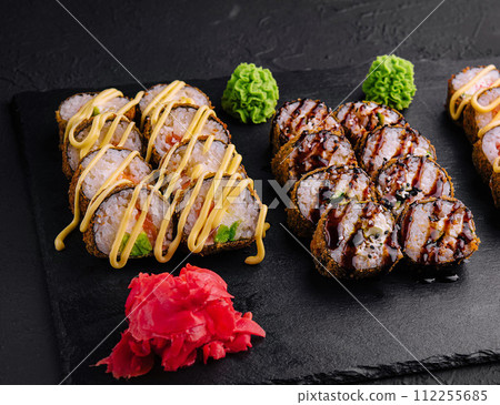 Set of baked sushi rolls with wasabi and ginger on black Set of baked sushi rolls with wasabi and ginger on black 112255685