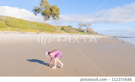 A little girl joyfully plays on the vast, empty sands of El Capitan State Beach in California during winter. A little girl joyfully plays on the vast, empty sands of El Capitan State Beach in California during winter. 112255686