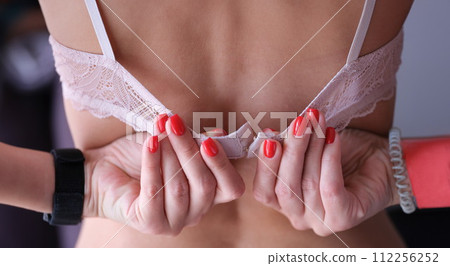 Underwear and beautiful manicured female hands unbutton bra 112256252