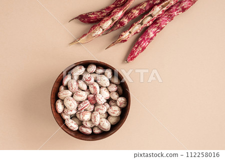 Cranberry beans. Borlotti bean pods in bowl. Top view. Stylish modern food background. Magenta color. Creative foodstuff flat lay. Grocery, dietary backdrop. Advertising, trendy magazine publication. 112258016